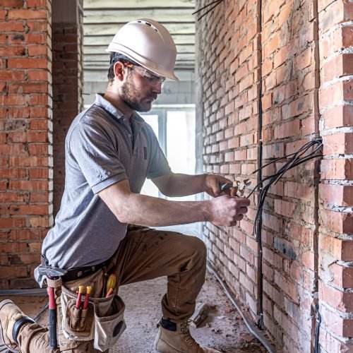A construction electrician cuts a voltage cable during a repair.