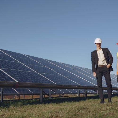 Businessman and worker near solar energy batteries. Business client showing photovoltaic detail to foreman. Two men making deal.
